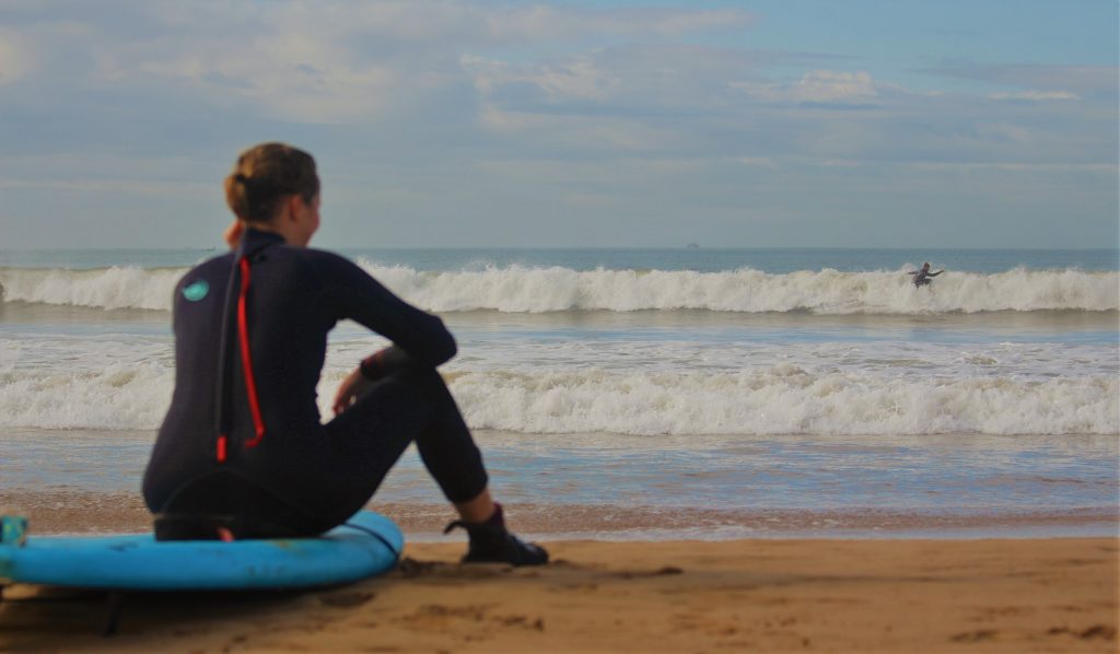 Junge Frau sitzt auf Surfbrett am Meer