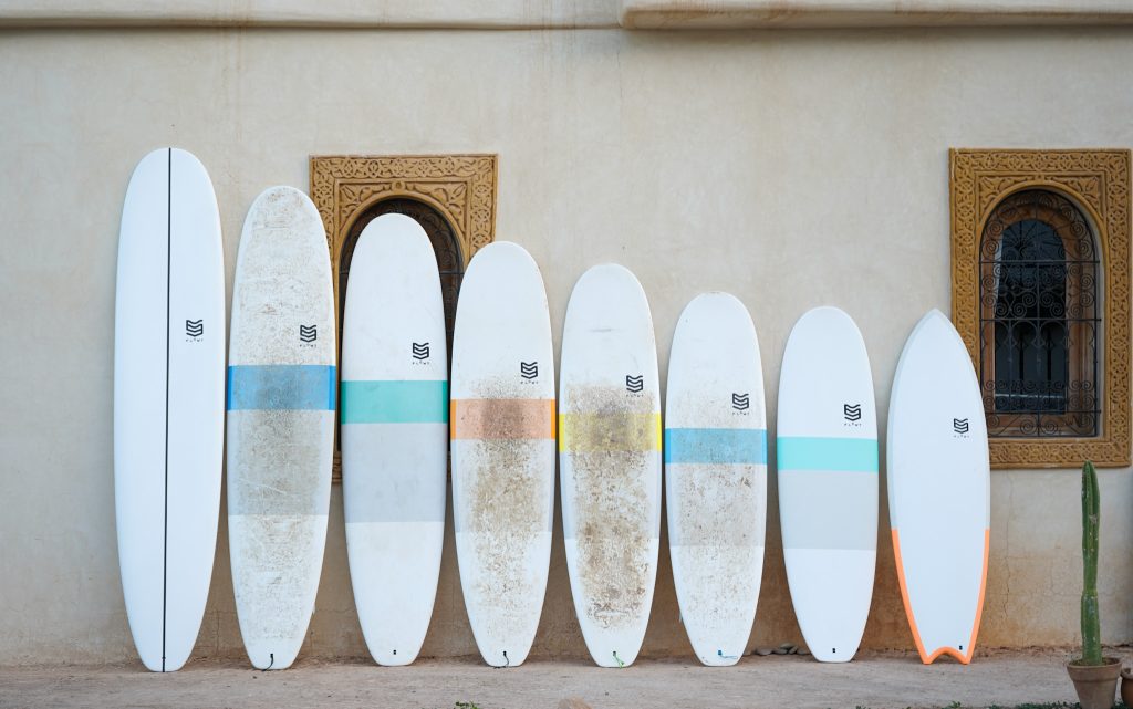 Surfboards in different shapes and sizes lined up in front of a wall