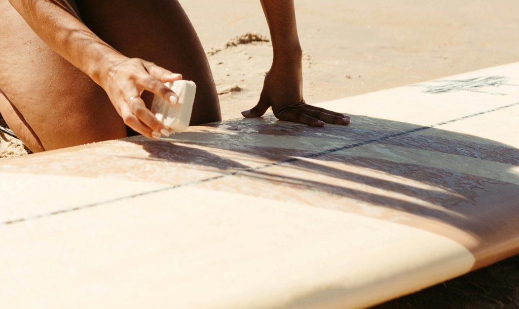 Woman putting wax on surfboard